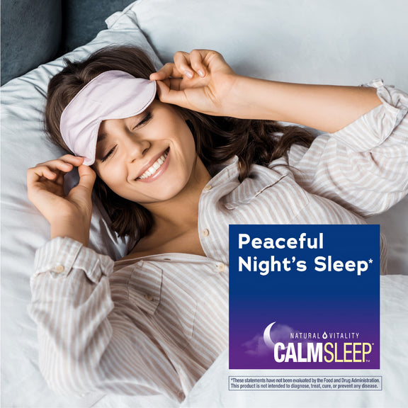 View 5 Young woman in bed smiling, adjusting a sleep mask next to a graphic for NATURAL VITALITY CALMSLEEP.