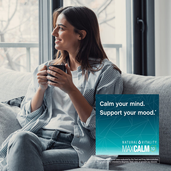 View 4 Young woman on couch with a mug, gazing out a window with a MaxCalm graphic.