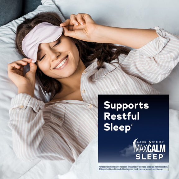 View 5 Young woman smiling in bed, removing a sleep mask, with an overlay for Natural Vitality MaxCalm Sleep.