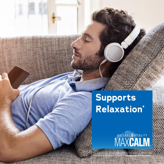 View 5 Young adult male relaxing on a couch with headphones, holding a phone, next to a graphic for MaxCalm.