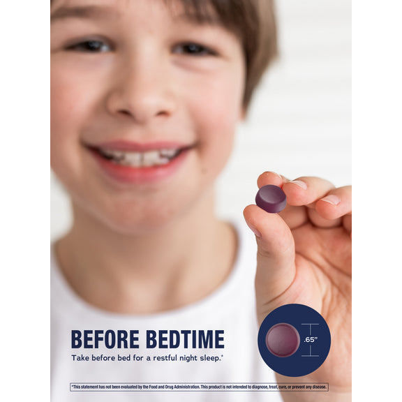 View 4 Young boy smiling while holding a small NV Kids Calm Sleep gummy.
