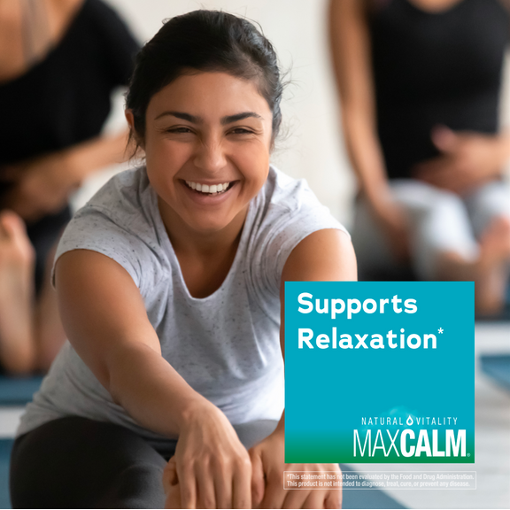 View 5 Woman smiling and stretching in a yoga class with a Natural Vitality Maxcalm graphic.