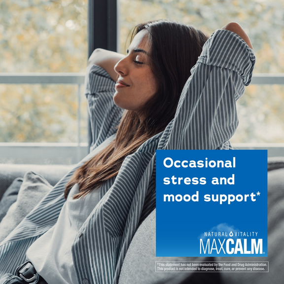 View 5 A young woman relaxes on a couch with closed eyes, next to a box of Natural Vitality Maxcalm.